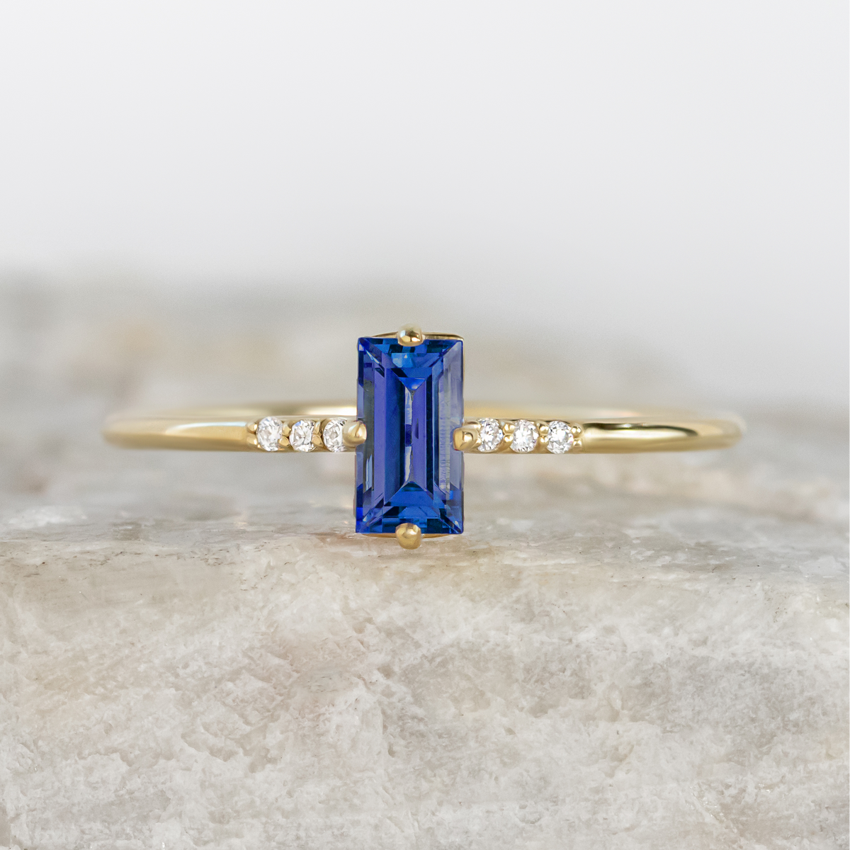Gold ring with a blue gemstone on a marble surface