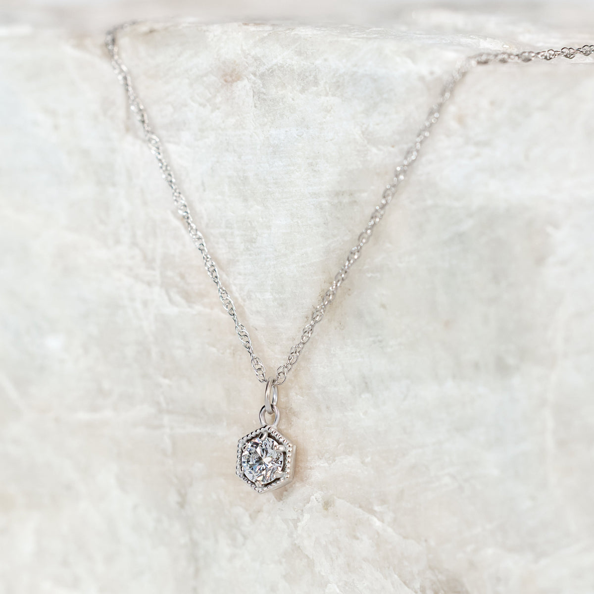 Silver necklace with a Diamond pendant on a white fur surface